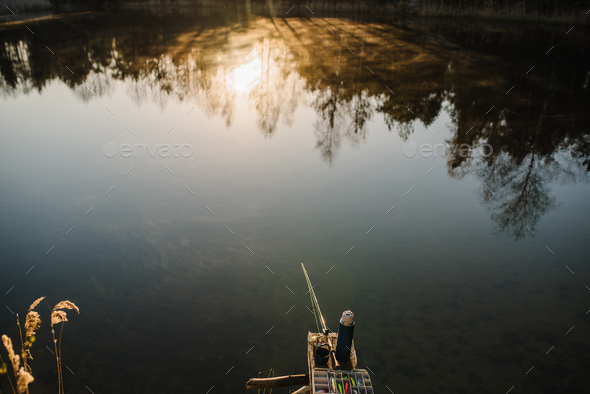 Fishing tackle - fishing spinning, rod, reel, hooks, fly, bait, lures in  box on wooden pier on pond Stock Photo by kurinchukolha