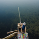 Fishing tackle - fishing spinning, rod, reel, hooks, fly, bait, lures in box  on wooden pier on pon Stock Photo by kurinchukolha