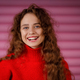 smiling young winter woman wearing winter red sweater indoors looking at camera with joyful smile. - PhotoDune Item for Sale