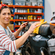 Portrait of smiling female mechanic cleaning motorcycle seat on factory - PhotoDune Item for Sale