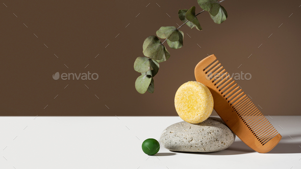 Modern geometric still life composition of a solid shampoo bar. Stone and wooden comb balancing