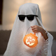 Little children wearing a white scary ghost costume holds a bucket of pumpkins for Halloween. - PhotoDune Item for Sale