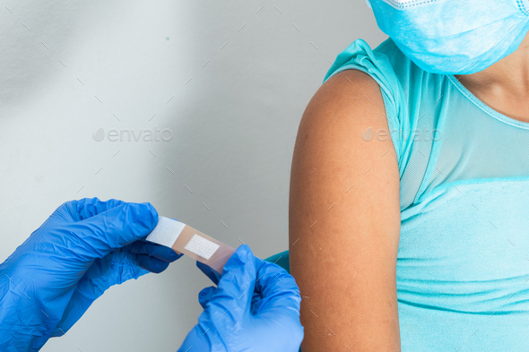 Doctor in putting an adhesive bandage on a girl\'s arm after injecting vaccine