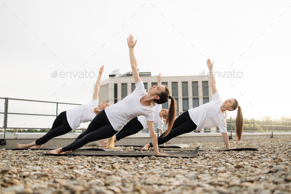 Yoginis breathing in Side Plank Pose during outdoor practice