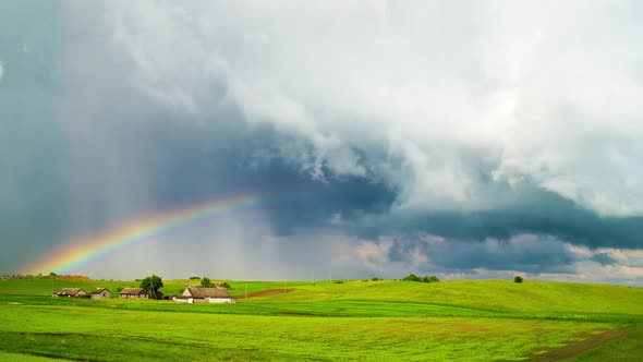 Rural landscape, rain clouds and rainbow alt