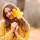 Young woman model in autumn park holds in her hand yellow foliage maple leaf at face - PhotoDune Item for Sale