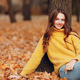Young woman sitting at tree in autumn park with yellow foliage maple leaves falls - PhotoDune Item for Sale