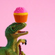Cute green dinosaur with pink icing cupcake on pink background. Copy space. - PhotoDune Item for Sale