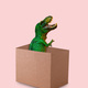 Funny green dinosaur sticks out of cardboard box on  pink background. Funny minimal greeting card. - PhotoDune Item for Sale