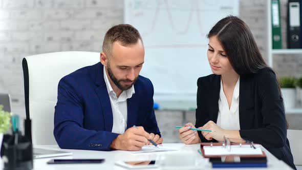 Male Boss Making Signature on Paper Contract Agreement Using Pen Looking on Data at Workplace alt