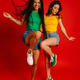 Full length of two happy young women in colorful wear dancing against red background - PhotoDune Item for Sale