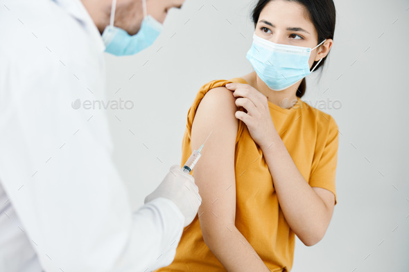 doctor in medical mask injecting a woman\'s shoulder vaccination injection health protection against