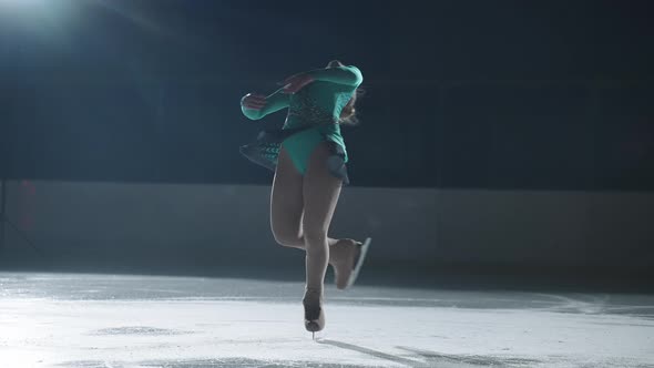 Young Female Figure Skater is Spinning on Ice in Darkness Competition and Demonstrative Performance alt