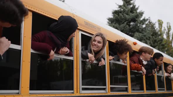 Joyful Teens with Heads Out of School Bus Windows alt