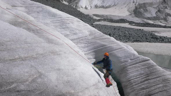 Mountaineer Man in Crampons Is Using Ascender on Fixed Rope on Steep Slope in Mountains alt