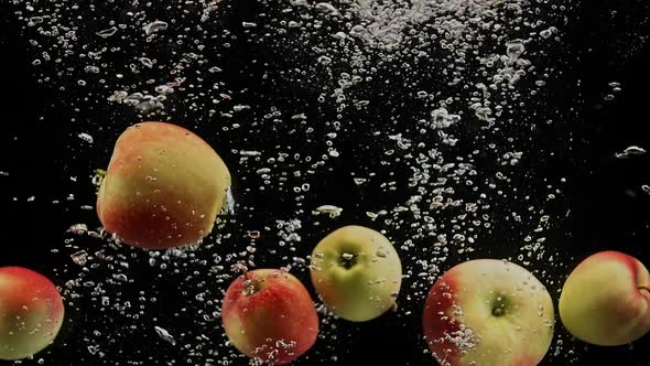 Red Apples Falling in Water with Splash and Air Bubbles on Black Background alt