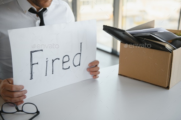 fired employee holding fired sign in hand