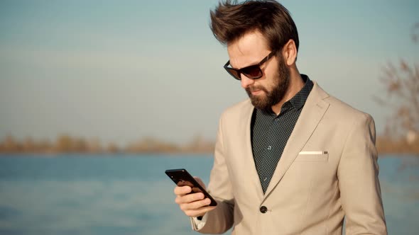 Freelancer Man Mobile Working Outdoors Walking And Using Cellphone. Businessman In Suit. alt