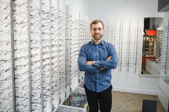 In Optics Shop. Portrait of male client holding and wearing different spectacles