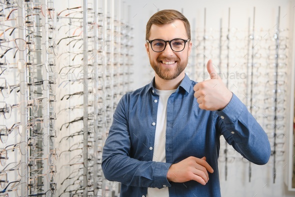 In Optics Shop. Portrait of male client holding and wearing different spectacles