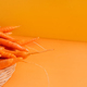 Ripe carrots in a wicker basket on an orange background - PhotoDune Item for Sale