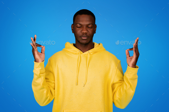 Positive calm young black man with closed eyes meditation enjoy free time rest