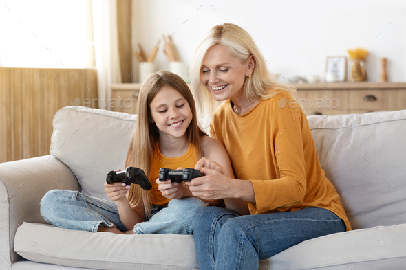 Cheerful girl showing grandma how to play video games