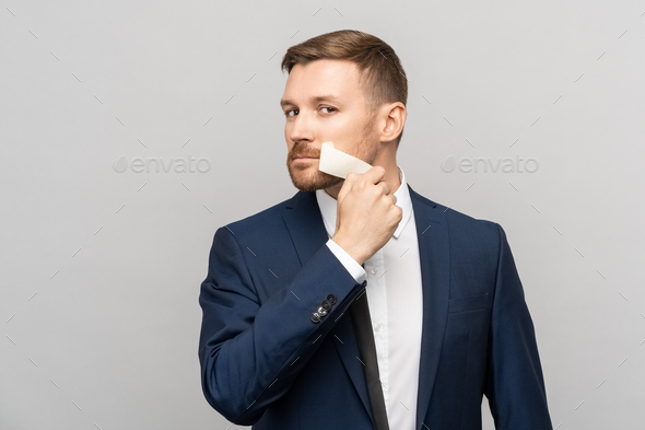 Office worker peels off tape from mouth on gray background looking at camera. Censorship concept.