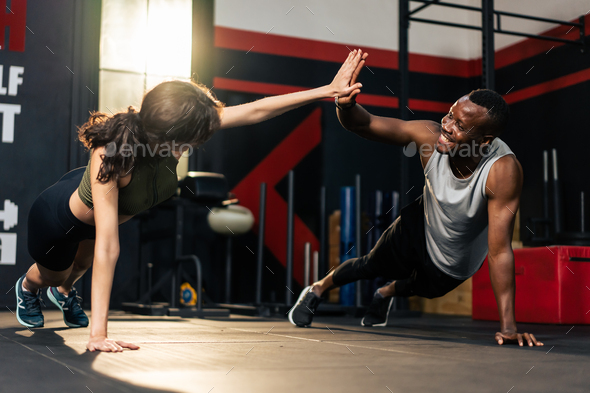 American African sportsman and Latino sportswoman work out together.