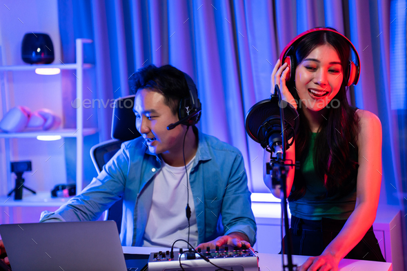 Asian audio DJ man and woman speaks into microphone to broadcasting.