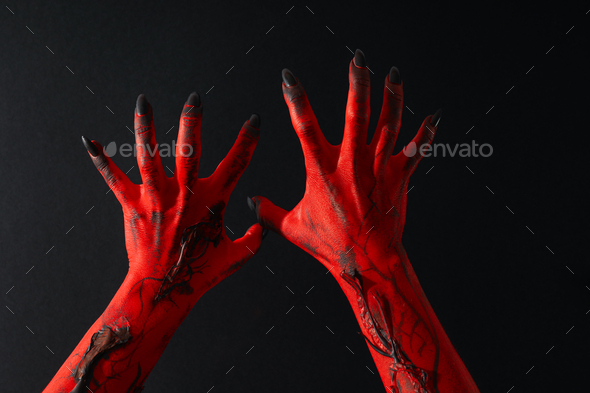 Creepy, red hands of a monster with black nails