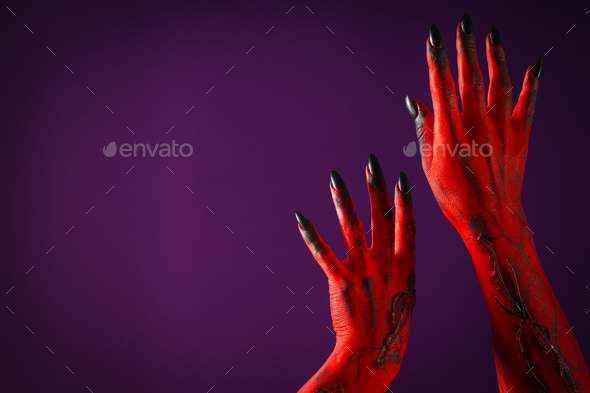 Creepy, red hands of a monster with black nails