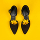 Suede black court shoes with yellow Topinambur flower bud inside toe, yellow background, womanhood - PhotoDune Item for Sale