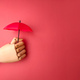 Wooden hand holding red umbrella on a red background with copy space. - PhotoDune Item for Sale
