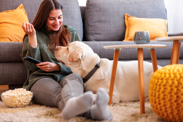 Woman and dog spending leisure time at home watching TV