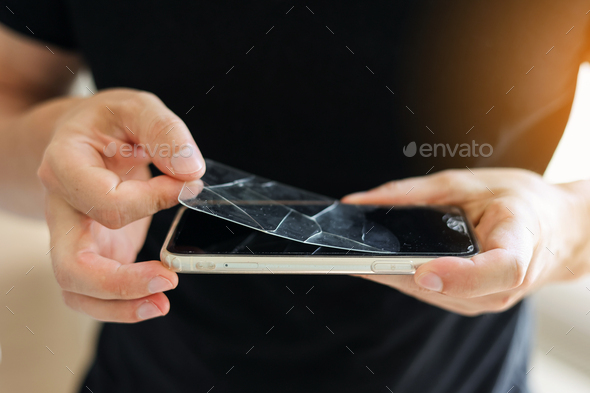 Process unrecognisable repairman is removing broken and old tempered glass screen protector from