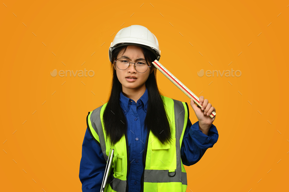 Teenage Asian girl wearing helmet isolated on yellow background, future dream job career.
