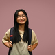 Smiling schoolgirl wearing glasses with backpack standing on pink background. - PhotoDune Item for Sale