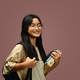 Asian schoolgirl with backpack holding books standing on pink background. - PhotoDune Item for Sale