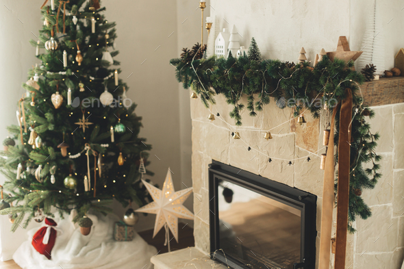 Stylish decorated fireplace mantel with christmas branches, decorations and bells
