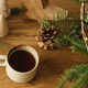 Stylish cup of warm tea, fir branches in basket, wooden trees and star, pine cones and lights - PhotoDune Item for Sale