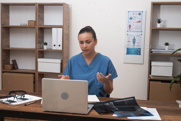 doctor scrutinizes talk to patient test results on her laptop during an online consultation