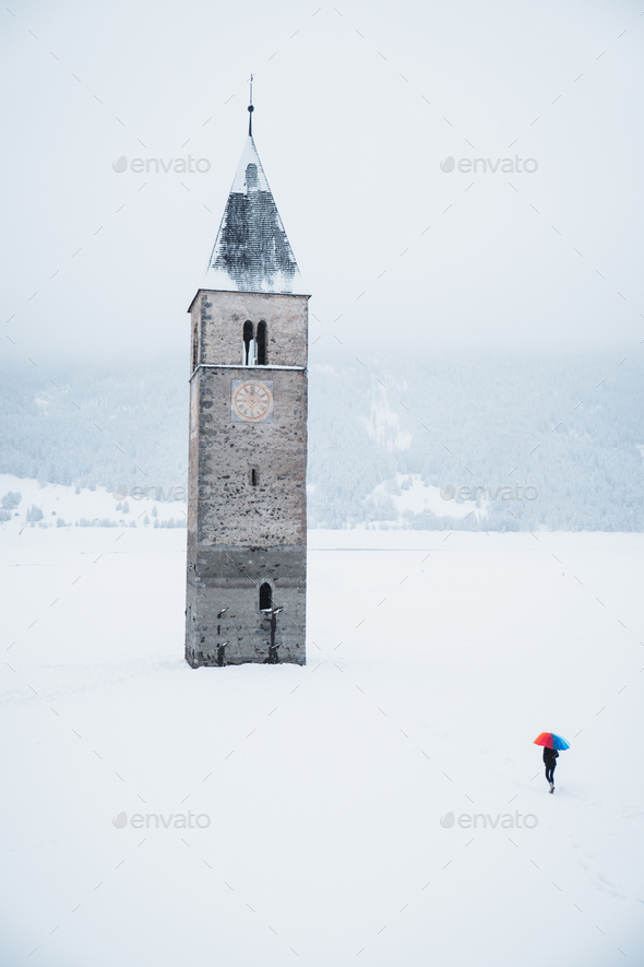 Portrait of the tower in the middle of the Lake Reschen during winter in South Tyrol, Italy - Stock Photo - Images
