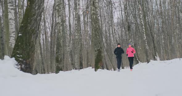 Man and Woman Run in the Park in Winter in Slow Motion alt