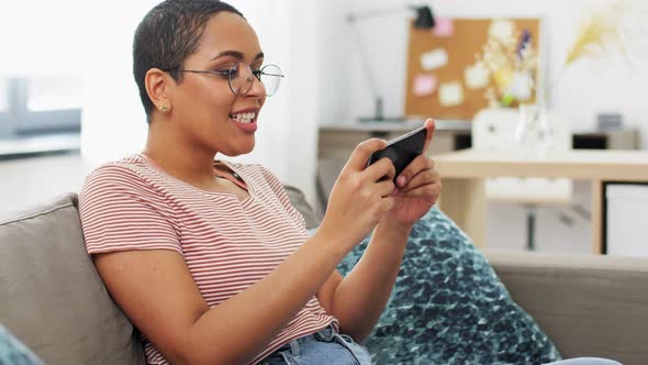 Happy Woman Playing Game on Smartphone at Home alt