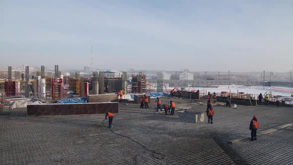 Builders in Orange Vests Work at Stadium Construction Site alt