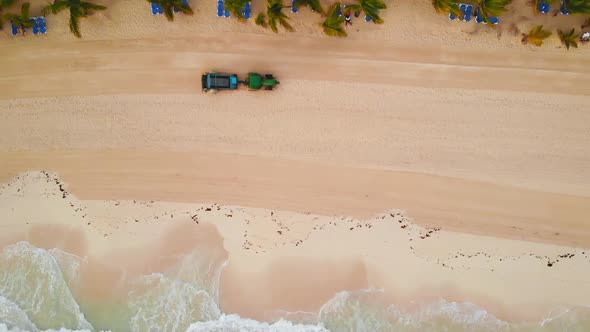Aerial View of Tractor Removes Debris and Algae on Sand Beach alt