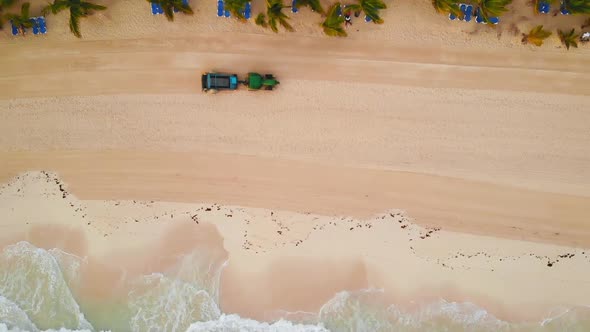 Aerial View of Tractor Removes Debris and Algae on Sand Beach