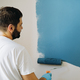 caucasian bearded man painting wall with paint roller. Painting apartment, renovating home - PhotoDune Item for Sale