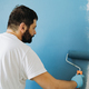 caucasian bearded man painting wall with paint roller. Painting apartment, renovating home - PhotoDune Item for Sale